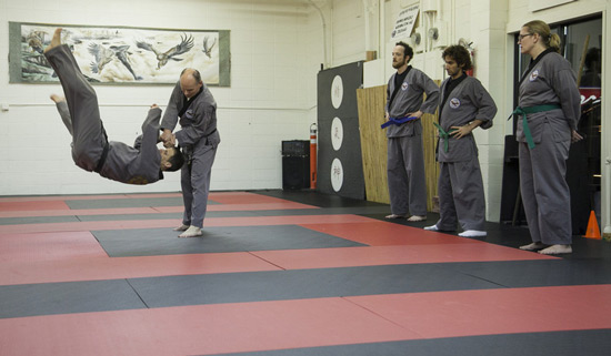 five people in martial artist gear practicing 