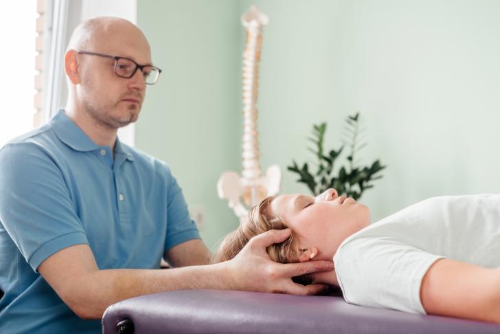 person with hands beneath someone's neck in craniosacral appointment
