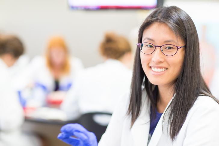 student in lab coat smiling at camera