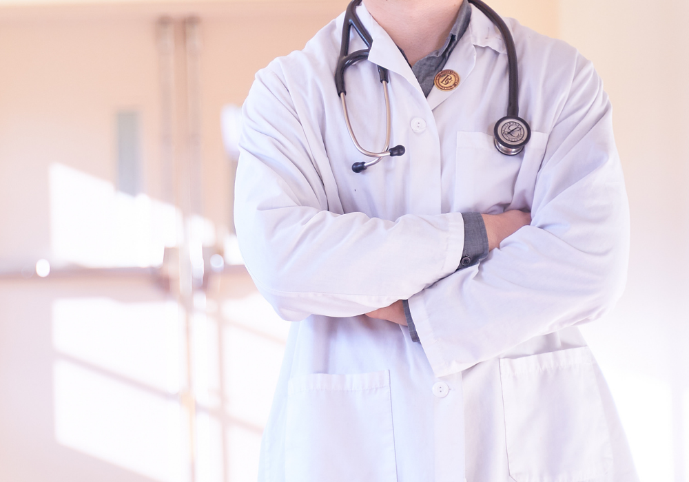 Person standing wearing white lab coat and stethoscope 