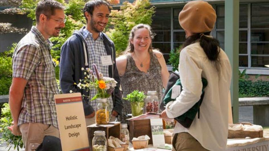 four people standing around a bastyr booth table