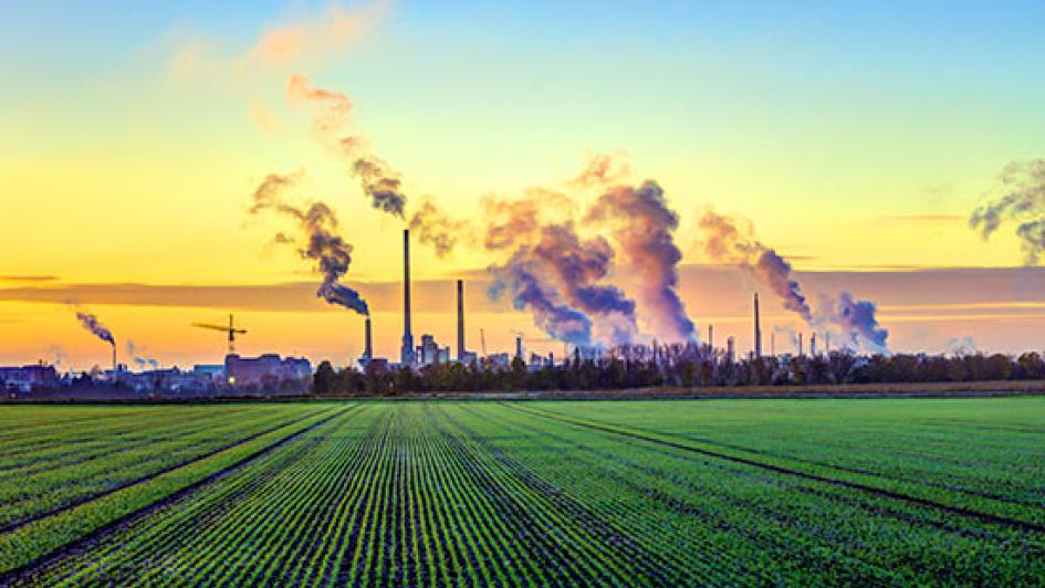 farm field with cityscape releasing exhaust into air