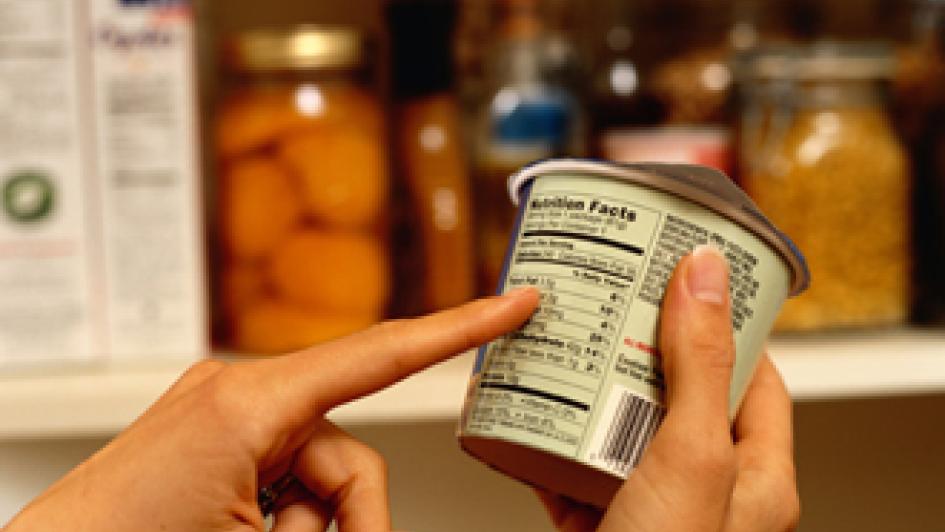 person pointing at nutrition facts on container