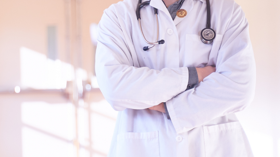 Person standing wearing white lab coat and stethoscope 