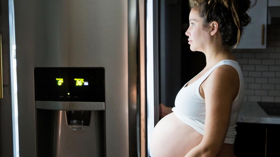 pregnat person standing in front of open refrigerator