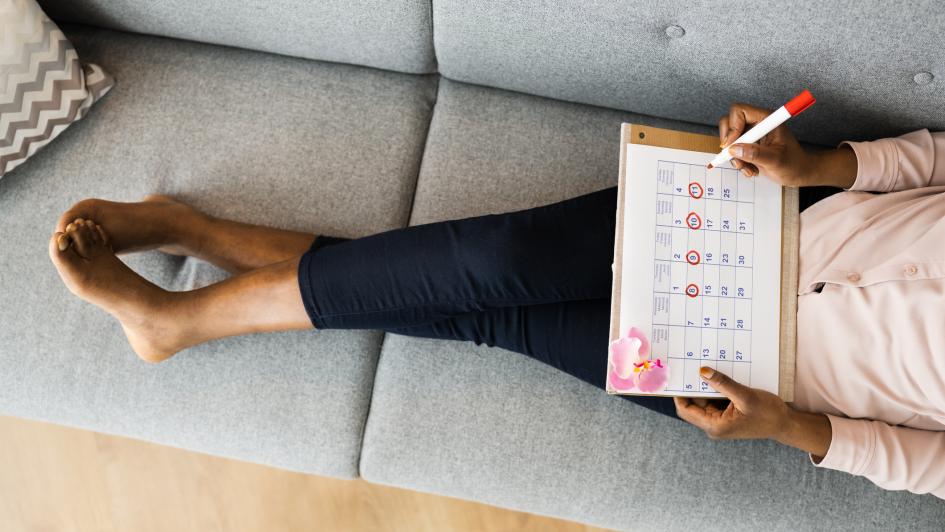 person sitting on couch looking at menstraul calendar