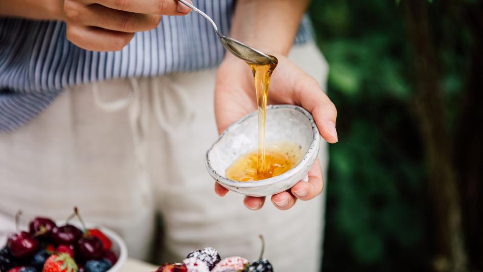 Close-up of a person using honey on breakfast food