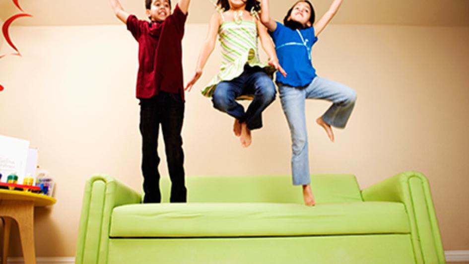 three children jumpong on green sofa