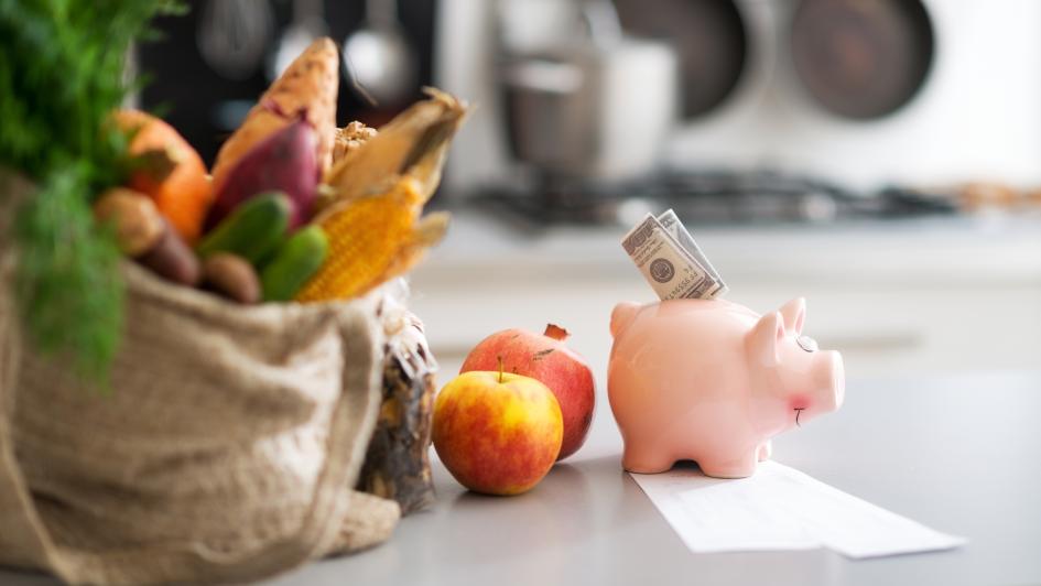 bag of fruits and vegetables next to a piggy bank
