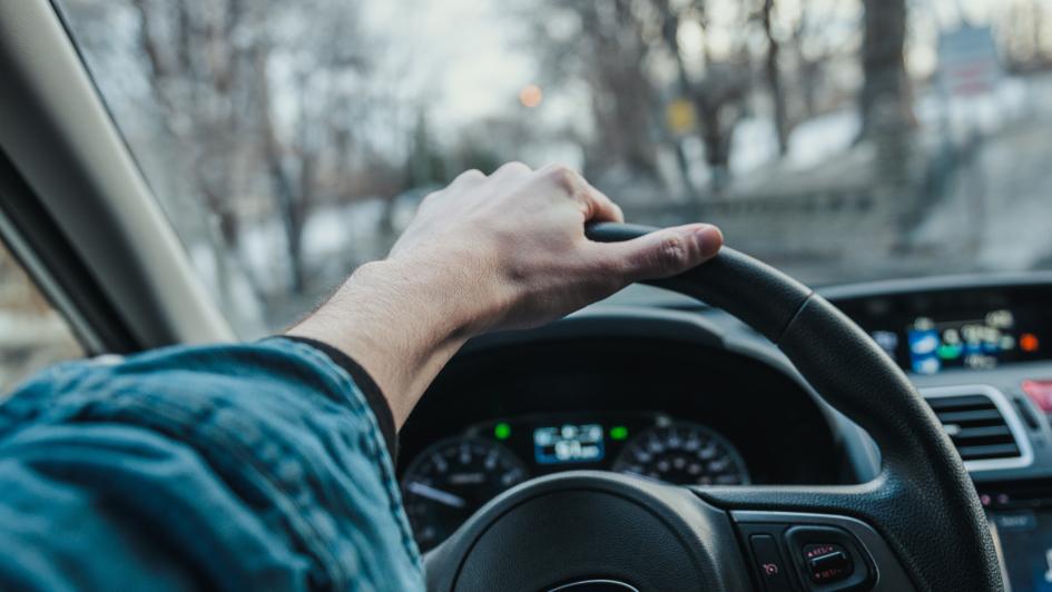 person's hand on steering wheel of vehicle