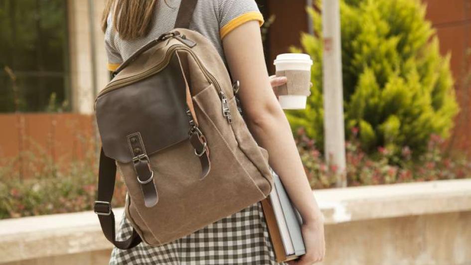 student walking with backpack and cup of coffee