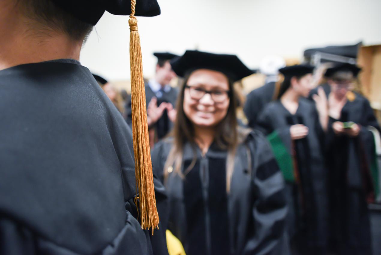 closeup of graduation cap with graduate in background smiling